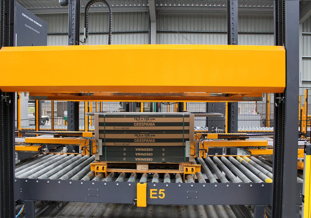 Pallet strapping system with edge protector applicator